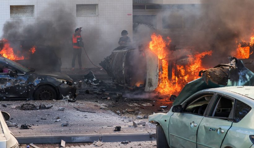TOPSHOT - People try to extinguish fire on cars following a rocket attack from the Gaza Strip in Ashkelon, southern Israel, on October 7, 2023. Palestinian militant group Hamas has launched a "war" against Israel, Defence Minister Yoav Gallant said, after barrages of rockets were fired from the Gaza Strip into Israeli territory on October 7. (Photo by AHMAD GHARABLI / AFP) (Photo by AHMAD GHARABLI/AFP via Getty Images)