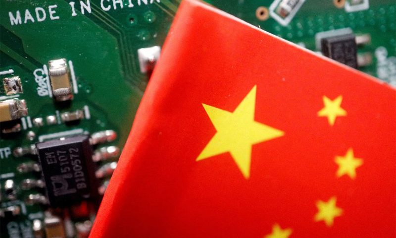 A Chinese flag is displayed next to a "Made in China" sign seen on a printed circuit board with semiconductor chips, in this illustration picture taken February 17, 2023. REUTERS/Florence Lo/Illustration/File Photo