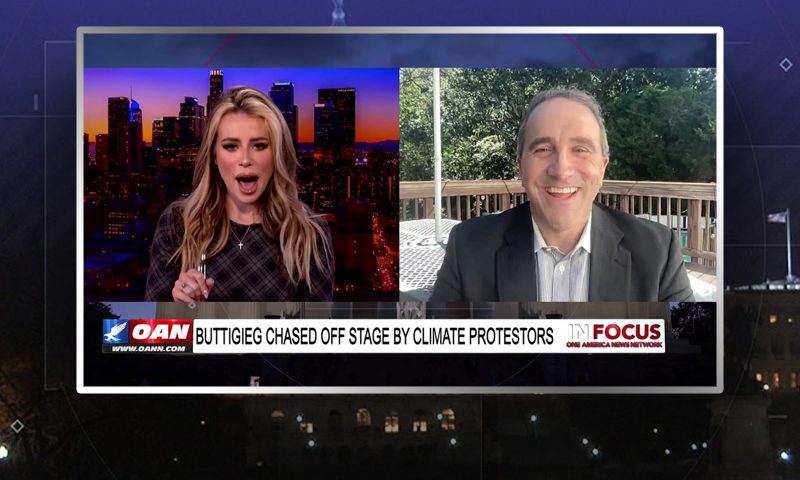 Video still from In Focus on One America News Network showing a split screen of the host on the left side, and on the right side is the guest, Marc Morano.