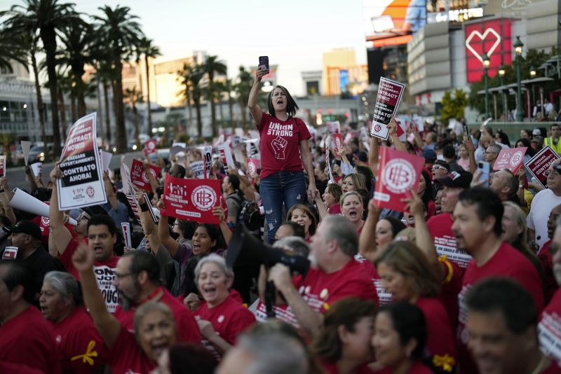 Members of the Culinary Workers Union rally along the Strip, Wednesday, Oct. 25, 2023, in Las Vegas. Thousands of hotel workers fighting for new union contracts rallied Wednesday night on the Las Vegas Strip, where rush-hour traffic was disrupted when some members blocked the road before being detained by police. (AP Photo/John Locher)