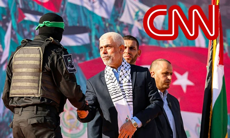 (L) Yahia al-Sinwar (C), Gaza Strip chief of the Palestinian Islamist Hamas movement, shakes hands with a masked fighter of Hamas' Qassam Brigades during a rally marking the 35th anniversary of the group's foundation, in Gaza City on December 14, 2022. - Hamas will end talks on securing a prisoner exchange with Israel unless there is progress soon, the militant group's leader in the Gaza Strip said on December 14. Since Israel's 2014 invasion of the Gaza Strip, the Islamist group has held the bodies of Israeli soldiers Oron Shaul and Hadar Goldin, although Hamas has never confirmed their deaths. Earlier this year Hamas published a video of an Israeli civilian detained for seven years in the enclave. (Photo by MOHAMMED ABED / AFP) (Photo by MOHAMMED ABED/AFP via Getty Images) (R) CNN logo graphic./ Canva edit.