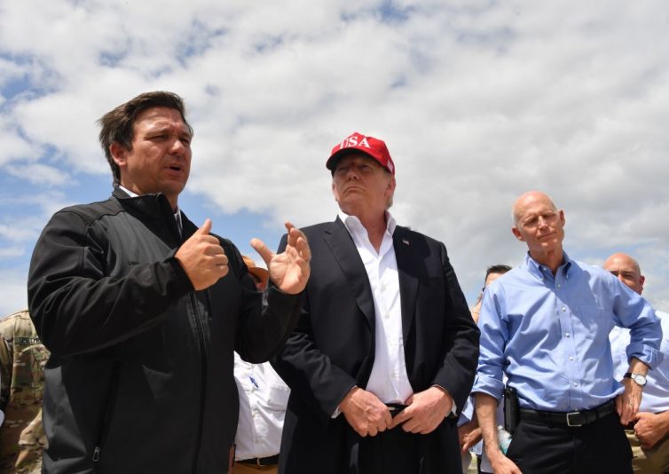 US President Donald Trump and Florida Republican US Senator Rick Scott (R) listen to Florida Governor Ron DeSantis (L) during a tour of the Edgar Hoover Dike on Lake Okeechobee in Florida, on March 29, 2019. (Photo by Nicholas Kamm / AFP) (Photo credit should read NICHOLAS KAMM/AFP via Getty Images)