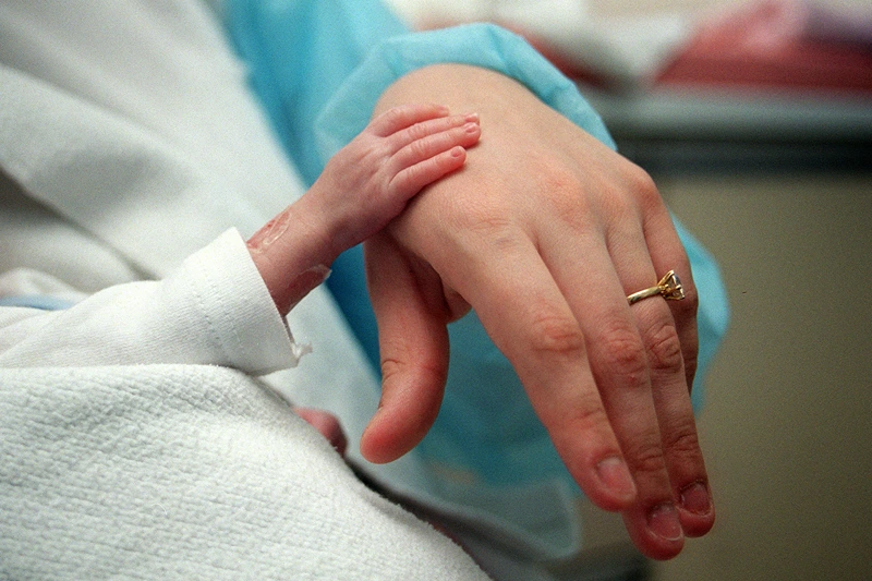 FRANCE-NEONATOLOGY-MEDICINE-PREMATURE
A premature baby poses on February 20, 2003, his hand on his mother's in the neonatology department of Robert Debré hospital in Paris. - Very premature infants are referred to this specialized intensive care unit because resuscitation is particularly cumbersome and sometimes accompanied by complications. A premature baby is a child born before the 37th week (8 months or 259 days) and whose all major functions are immature (respiratory, immune, digestive). Approximately 44,000 children are born prematurely each year in France. Prematurity thus reaches 5.9% of births in France. AFP PHOTO DIDIER PALLAGES (Photo by Didier PALLAGES / AFP) (Photo credit should read DIDIER PALLAGES/AFP via Getty Images)