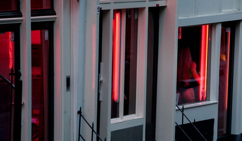 A prostitute is pictured through a window in the red light district of Amsterdam on July 1, 2020, as Dutch brothels reopened today after a long coronavirus shutdown, with sex workers and clients having to observe new rules to prevent COVID-19 infection. The Netherlands ordered all sex clubs closed in mid-March and had originally planned to keep them closed until September, but recently brought the date forward as COVID-19 cases dropped. (Photo by Kenzo TRIBOUILLARD / AFP) (Photo by KENZO TRIBOUILLARD/AFP via Getty Images)