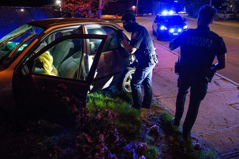 Officer Daniel Arteaga and other officers inspect the car that they were chasing, now crashed into a fence after hitting a fire hydrant in Chelsea, Massachusetts on May 1, 2021. - Chelsea, a 2.2 square-mile (5.7 square km) city, has a population of close to 40,000 people made up of mostly people of Latino or Hispanic origin, 67% according to the US Census Bureau. The Bureau also reports that 18% of the population lives at the poverty line.  The Chelsea Police Department considers itself ahead of many parts of theUS when it comes to community policing and the way it deals with de-escalating domestic and criminal situations. (Photo by Joseph Prezioso / AFP) (Photo by JOSEPH PREZIOSO/AFP via Getty Images)