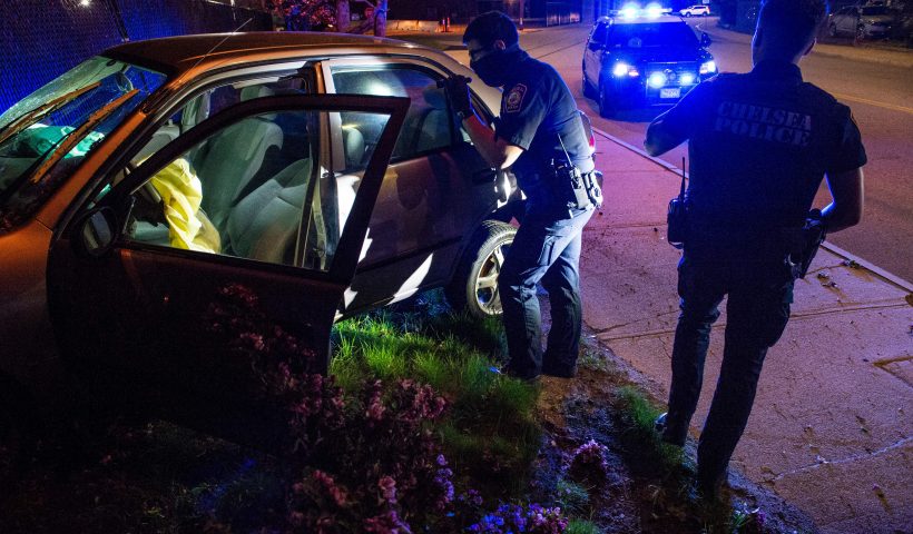 Officer Daniel Arteaga and other officers inspect the car that they were chasing, now crashed into a fence after hitting a fire hydrant in Chelsea, Massachusetts on May 1, 2021. - Chelsea, a 2.2 square-mile (5.7 square km) city, has a population of close to 40,000 people made up of mostly people of Latino or Hispanic origin, 67% according to the US Census Bureau. The Bureau also reports that 18% of the population lives at the poverty line. The Chelsea Police Department considers itself ahead of many parts of theUS when it comes to community policing and the way it deals with de-escalating domestic and criminal situations. (Photo by Joseph Prezioso / AFP) (Photo by JOSEPH PREZIOSO/AFP via Getty Images)