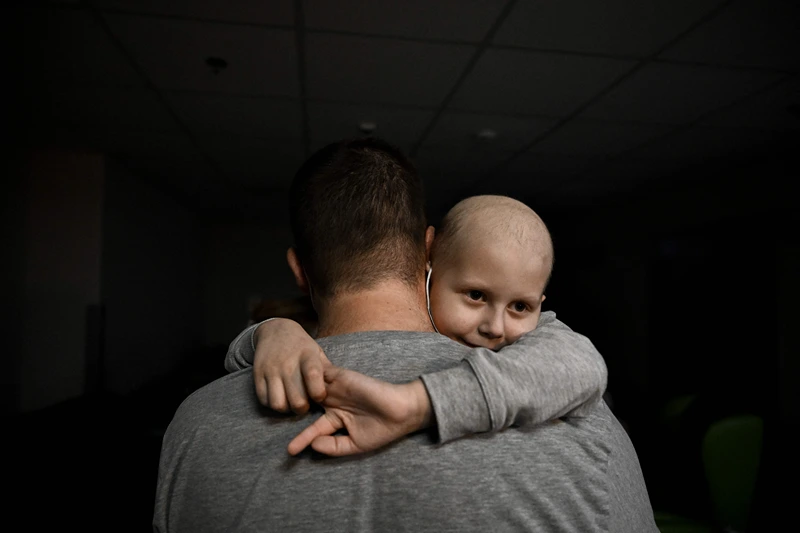 UKRAINE-RUSSIA-HOSPITAL-CONFLICT
A child struggling with cancer is held by an adult in the basement of the oncology centre used as a bomb shelter, in Kyiv on February 28, 2022. - The Russian army said on February 28, 2022, that Ukrainian civilians could 