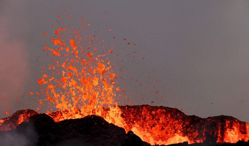 TOPSHOT - People watch flowing lava during an volcanic eruption near Litli Hrutur, south-west of Reykjavik in Iceland on July 10, 2023. A volcanic eruption started on July 10, 2023 around 30 kilometres (19 miles) from Iceland's capital Reykjavik, the country's meteorological office said, marking the third time in two years that lava has gushed out in the area. "The eruption is taking place in a small depression just north of Litli Hrutur, from which smoke is escaping in a north-westerly direction," the office said. Footage circulating in the local media shows a massive cloud of smoke rising from the ground as well as a substantial flow of lava. (Photo by Kristinn Magnusson / AFP) / Iceland OUT (Photo by KRISTINN MAGNUSSON/AFP via Getty Images)