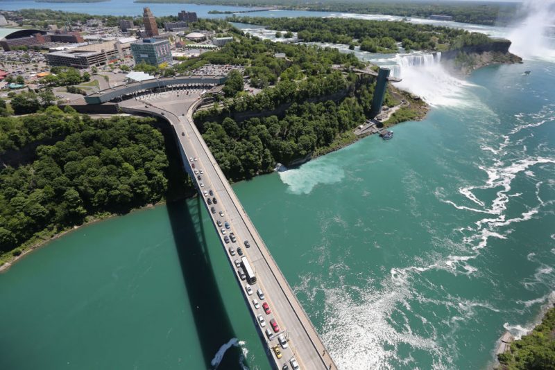 NIAGARA FALLS, NY - JUNE 04: The Rainbow Bridge crosses from the United States (L), into Canada near the Niagara Falls on June 4, 2013 at Niagara Falls, New York. The falls, which have a combined highest flow rate of any waterfall in the world, straddle the U.S.-Canada border, on the Niagara River, which drains Lake Erie into Lake Ontario. The falls, visited by millions of tourists on each side of the border, are also a major source of hydroelectric power for the region. The aerial view was seen from a helicopter flown by the U.S. Office of Air and Marine, (OAM), which monitors and patrols the U.S. northern border with Canada. (Photo by John Moore/Getty Images)