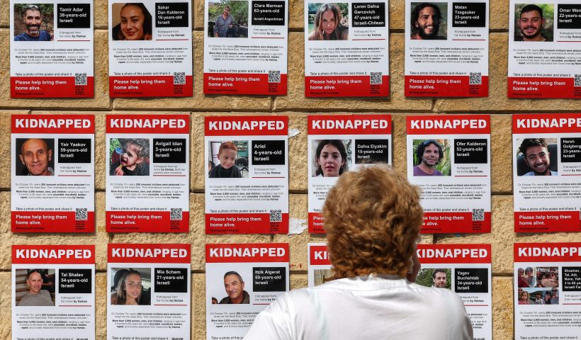 TOPSHOT - A woman looks at posters showing the pictures of Israeli hostages held by Palestinian militants since the October 7 attack, near Azrieli Mall in Tel Aviv on October 18, 2023. (Photo by AHMAD GHARABLI / AFP) (Photo by AHMAD GHARABLI/AFP via Getty Images)