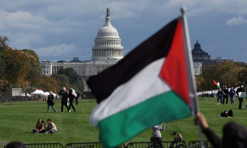 WASHINGTON, DC - OCTOBER 21: A pro-Palestinian protester waves a Palestinian flag on the National Mall during a demonstration calling for a ceasefire in Gaza on October 21, 2023 in Washington, DC. Thousands of pro-Palestinian protesters staged a rally near the Washington Monument to demand a ceasefire in Gaza as the war between Israel continues. Israel has heavily bombed the Gaza Strip and threatened a ground invasion after Hamas, the Palestinian militant group that governs the Gaza Strip, launched a deadly attack in southern Israel on October 7. (Photo by Justin Sullivan/Getty Images)
