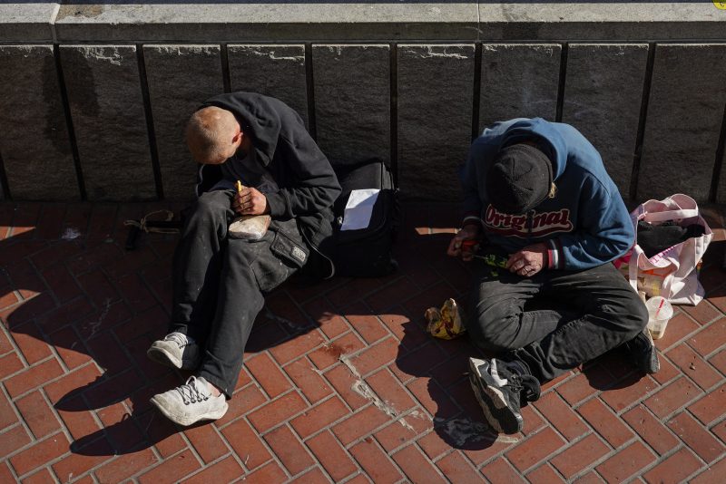Homeless people sit against a public transit station wall near APEC Summit headquarters on November 11, 2023 in downtown San Francisco, California. The city took steps to clean up in advance of the APEC Summit, currently taking place through November 17. (Photo by Loren Elliott / AFP) (Photo by LOREN ELLIOTT/AFP via Getty Images)