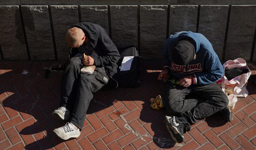Homeless people sit against a public transit station wall near APEC Summit headquarters on November 11, 2023 in downtown San Francisco, California. The city took steps to clean up in advance of the APEC Summit, currently taking place through November 17. (Photo by Loren Elliott / AFP) (Photo by LOREN ELLIOTT/AFP via Getty Images)