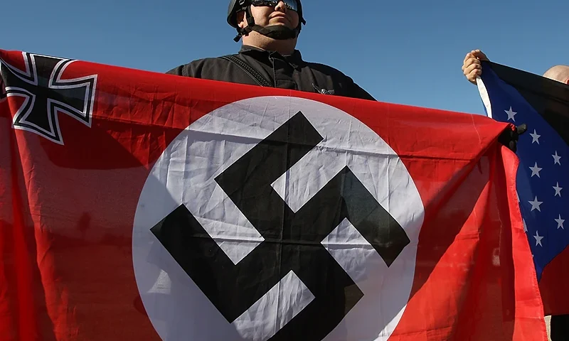 RIVERSIDE, CA - OCTOBER 24: Members of the white supremacist group, the National Socialist Movement, hold swastika flags at the NSMÕs anti-illegal immigration rally near a Home Depot store on October 24, 2009 in Riverside, California. It is the second such demonstration in Riverside by the Detroit-based Neo-Nazi group in the past month. The last rally was soon broken up by police after clashes with counter-protesters. (Photo by David McNew/Getty Images)