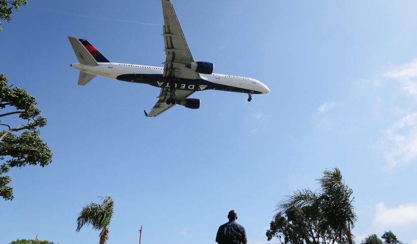 LOS ANGELES, CA - JULY 12: A man watches as a Delta Air Lines plane lands at Los Angeles International Airport on July 12, 2018 in Los Angeles, California. Delta announced today that it will increase fares by reducing the supply of seats in an effort to offset higher fuel prices. (Photo by Mario Tama/Getty Images)