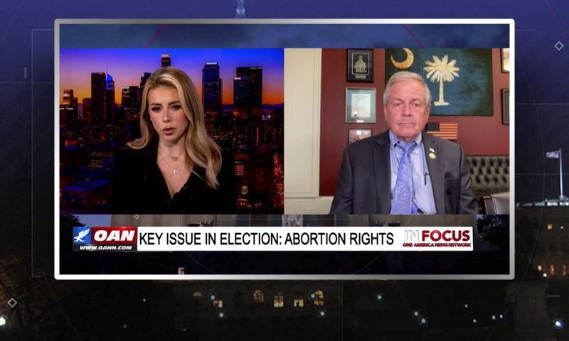 Video still from In Focus on One America News Network showing a split screen of the host on the left side, and on the right side is the guest, Ralph Norman.