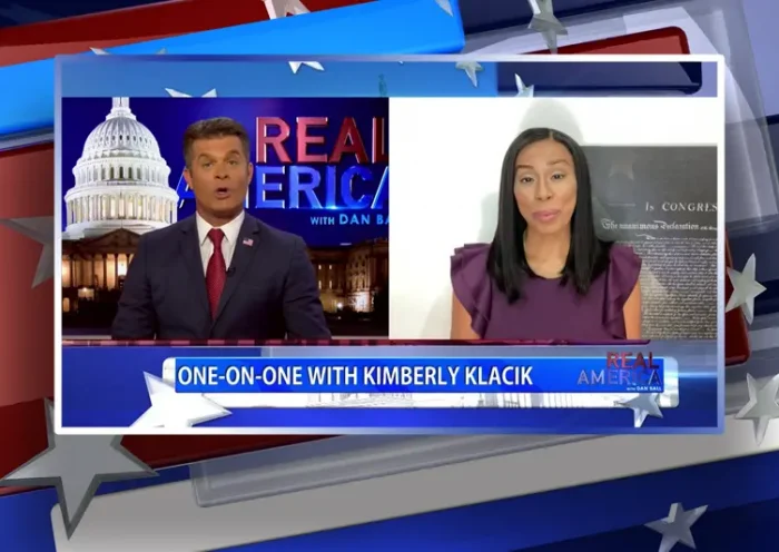 Video still from Real America on One America News Network showing a split screen of the host on the left side, and on the right side is the guest, Kim Klacik.