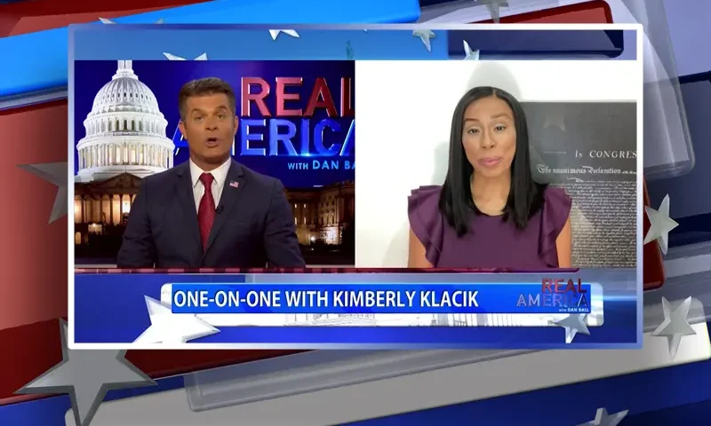 Video still from Real America on One America News Network showing a split screen of the host on the left side, and on the right side is the guest, Kim Klacik.