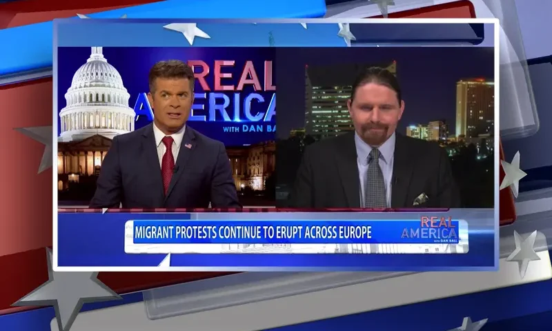 Video still from Real America on One America News Network showing a split screen of the host on the left side, and on the right side is the guest, Seamus Bruner.