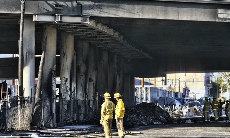 of 10 | Firefighters assess the damage from a intense fire under Interstate 10 that severely damaged the overpass in an industrial zone near downtown Los Angeles on Saturday, Nov. 11, 2023. Authorities say firefighters have mostly extinguished a large blaze that burned trailers, cars and other things in storage lots beneath a major highway near downtown Los Angeles, forcing the temporary closure of the roadway. (AP Photo/Richard Vogel)