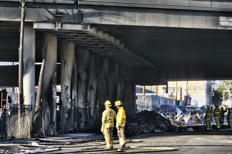 of 10 | Firefighters assess the damage from a intense fire under Interstate 10 that severely damaged the overpass in an industrial zone near downtown Los Angeles on Saturday, Nov. 11, 2023. Authorities say firefighters have mostly extinguished a large blaze that burned trailers, cars and other things in storage lots beneath a major highway near downtown Los Angeles, forcing the temporary closure of the roadway. (AP Photo/Richard Vogel)
