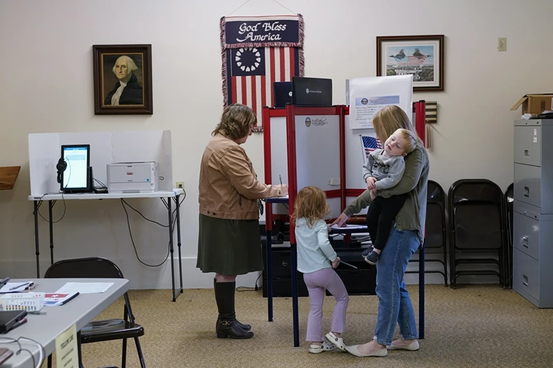 Lauren Miracle, right, holds her son Dawson, 1, as she helps her daughter Oaklynn, 3, fill out a child's practice ballot before voting herself at a polling location in the Washington Township House in Oregonia, Ohio, Tuesday, Nov. 7. Polls are open in a few states for off- year elections that could give hints of voter sentiment ahead of next year's critical presidential contest. (AP Photo/Carolyn Kaster)
