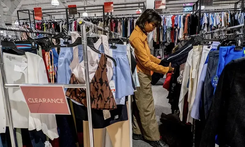 A person picks out clothing in a store as retailers compete to attract shoppers and try to maintain margins on Black Friday, one of the busiest shopping days of the year, at Woodbury Common Premium Outlets in Central Valley, New York, U.S. November 24, 2023. REUTERS/Vincent Alban/File Photo