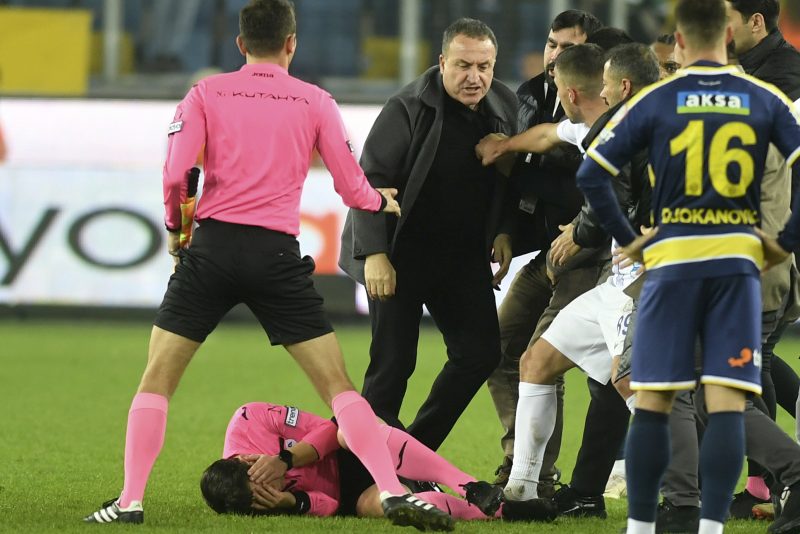 Referee Halil Umut Meler holds his face as he lies on the ground after being punched by MKE Ankaragucu president Faruk Koca, center, at the end of the Turkish Super Lig soccer match between MKE Ankaragucu and Caykur Rizespor in Ankara, Monday, Dec. 11, 2023. The Turkish Football Federation has suspended all league games in the country after a club president punched the referee in the face at the end of a top-flight match. Koca was arrested Tuesday, Dec. 12, 2023, along with two other people on charges of injuring a public official following questioning by prosecutors. (Abdurrahman Antakyali/Depo Photos via AP)