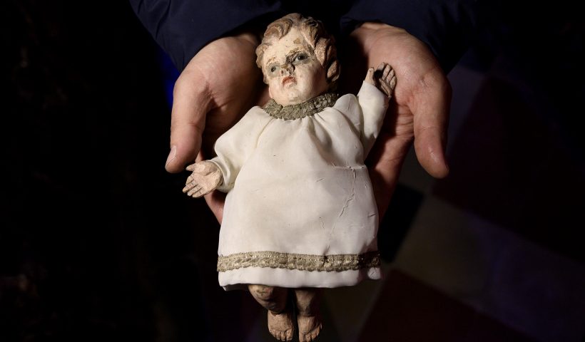 TOPSHOT - Volunteer Matteo Seia holds a nativity figure of Jesus, one of the most ancient figures of the 43rd edition of the "Presepio of Cavallermaggiore", a 300sqm Christmas Nativity crib in the Oratorio San Michele on December 20, 2019 in Cavallermaggiore, near Cuneo, Northwestern Italy. - The "Presepio" is made by ten volunteers who every year spend 3 months to build a new edition with hundred of figures. (Photo by MARCO BERTORELLO / AFP) (Photo by MARCO BERTORELLO/AFP via Getty Images)