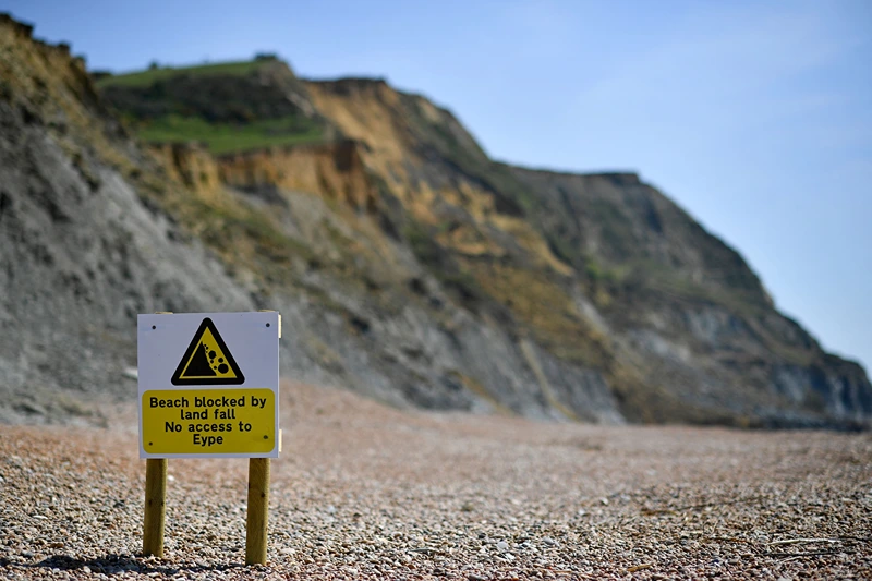 BRITAIN-EROSION-COAST
An advisory notice is seen on the beach close to the scene of a coastal cliff fall on Dorset's Jurassic Coast near the village of Seatown, on the south west coast of England on April 26, 2021. (Photo by BEN STANSALL / AFP) (Photo by BEN STANSALL/AFP via Getty Images)