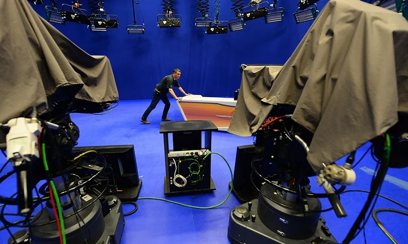 A cameraman pushes the table of a news studio of the independent tv network RTL Klub, Hungary's largest commercial media company in Budapest on June 5, 2014. Hungary's media companies are up in arms over a proposed tax on adverts that industry insiders say would cripple the sector as well as tighten the government's hold on the press. Over 60 companies, including TV channels, radio stations, newspapers and websites are going off-air, or printing black front pages in protest at the proposed bill, which would slap a tax of up to 40 percent on ad revenue. AFP PHOTO / ATTILA KISBENEDEK (Photo by Attila KISBENEDEK / AFP) (Photo by ATTILA KISBENEDEK/AFP via Getty Images)