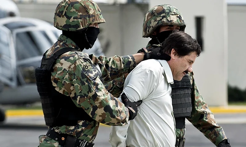 Mexican drug trafficker Joaquin Guzman Loera aka "el Chapo Guzman", is escorted by marines as he is presented to the press on February 22, 2014 in Mexico City. The Sinaloa cartel leader - the most wanted by US and Mexican anti-drug agencies - was arrested early this morning by Mexican marines at a resort in Mazatlan, northern Mexico. AFP PHOTO/RONALDO SCHEMIDT (Photo by Ronaldo SCHEMIDT / AFP) (Photo by RONALDO SCHEMIDT/AFP via Getty Images)