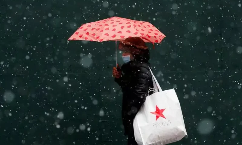 A woman carrying a Macy's bag walks in falling snow as a winter storm moves into the northeast of the United States, in Times Square in New York City, New York, U.S., January 26, 2021. REUTERS/Mike Segar/File photo