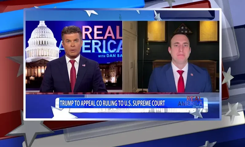 Video still from Real America on One America News Network showing a split screen of the host on the left side, and on the right side is the guest, Mike Yoder.