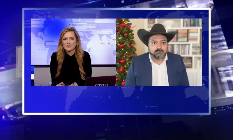 Video still from The Real Story on One America News Network showing a split screen of the host on the left side, and on the right side is the guest, Burt Thakur.