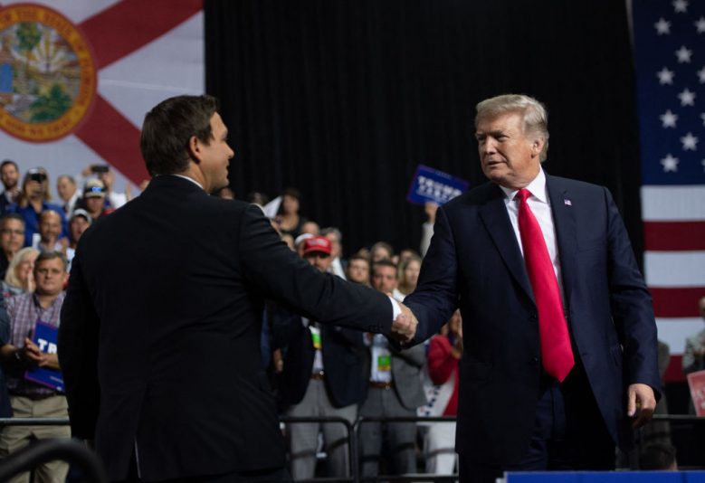 US President Donald Trump shakes hands with US Representative Ron DeSantis, Republican of Florida, and candidate for Florida Governor, as he speaks during a campaign rally at Florida State Fairgrounds Expo Hall in Tampa, Florida, on July 31, 2018. (Photo by SAUL LOEB / AFP) (Photo by SAUL LOEB/AFP via Getty Images)