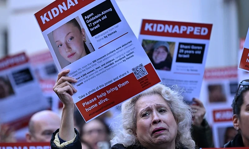 A poster showing the kidnapped Israeli Agam Goldstein-Almog is held up as people gather outside the Qatari Embassy in London on October 29, 2023, to demand the release of the estimated 230 hostages held in Gaza by Hamas after the attacks inside Israel on October 7. Thousands of civilians, both Palestinians and Israelis, have died since October 7, 2023, after Palestinian Hamas militants based in the Gaza Strip entered southern Israel in an unprecedented attack triggering a war declared by Israel on Hamas with retaliatory bombings on Gaza. (Photo by Justin TALLIS / AFP) (Photo by JUSTIN TALLIS/AFP via Getty Images)