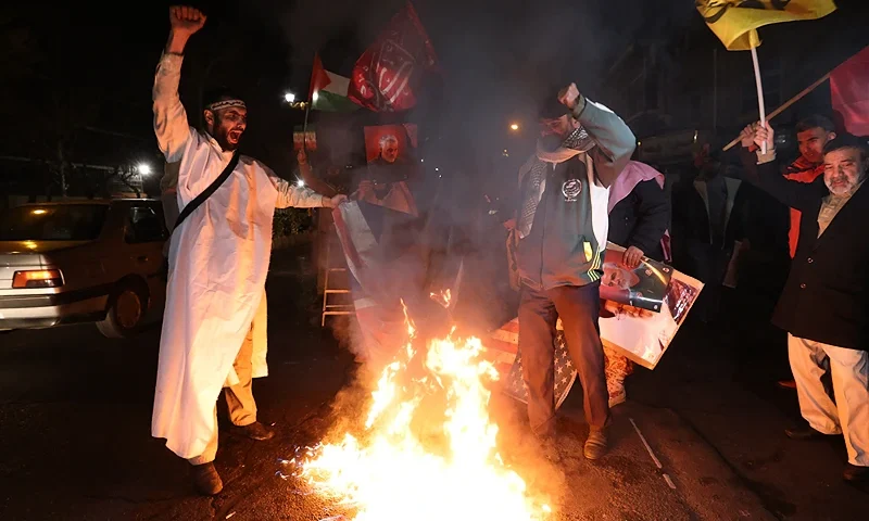 Iranian protesters burn an Israeli and a US flag during a demonstration in solidarity with the Palestinian people and Iran-backed Yemeni rebels following US and British forces strikes on Huthi rebel-held cities in Yemen, in front of the British embassy in Tehran on January 12, 2024 amid the ongoing battles between Israel and the militant Hamas group in Gaza. US and British forces struck rebel-held Yemen early on January 12, after weeks of disruptive attacks on Red Sea shipping by the Iran-backed Huthis who say they act in solidarity with Gaza. The pre-dawn air strikes add to escalating fears of wider conflict in the region, where violence involving Tehran-aligned groups in Yemen as well as Lebanon, Iraq and Syria has surged since the Israel-Hamas was began in early October. (Photo by ATTA KENARE / AFP) (Photo by ATTA KENARE/AFP via Getty Images)