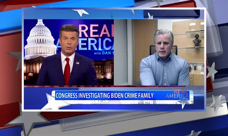 Video still from Real America on One America News Network showing a split screen of the host on the left side, and on the right side is the guest, Tom Fitton.