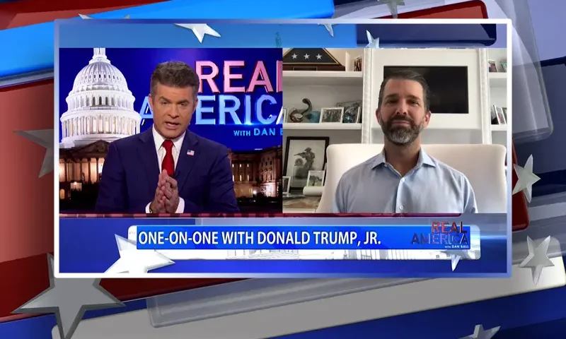 Video still from Real America on One America News Network showing a split screen of the host on the left side, and on the right side is the guest, Donald Trump Jr.