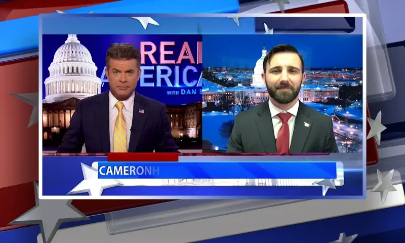 Video still from Real America on One America News Network showing a split screen of the host on the left side, and on the right side is the guest, Cameron Hamilton.