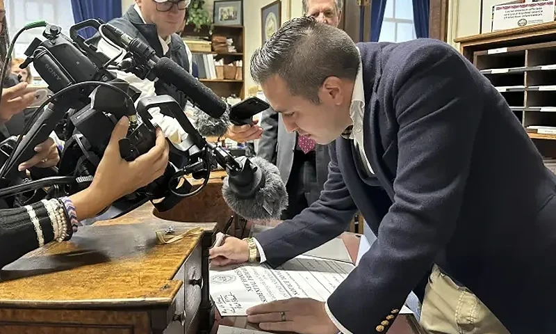 John Anthony Castro, of Texas, signs a commemorative poster after filing to get on the Republican ballot for the 2024 New Hampshire primary in Concord, N.H., on Wednesday, Oct. 11, 2023. Castro, who has filed multiple lawsuits contending the 14th Amendment bars former President Donald Trump's candidacy, wrote: "Freedom comes from our Constitution. Without that we fall." (AP Photo/Holly Ramer)