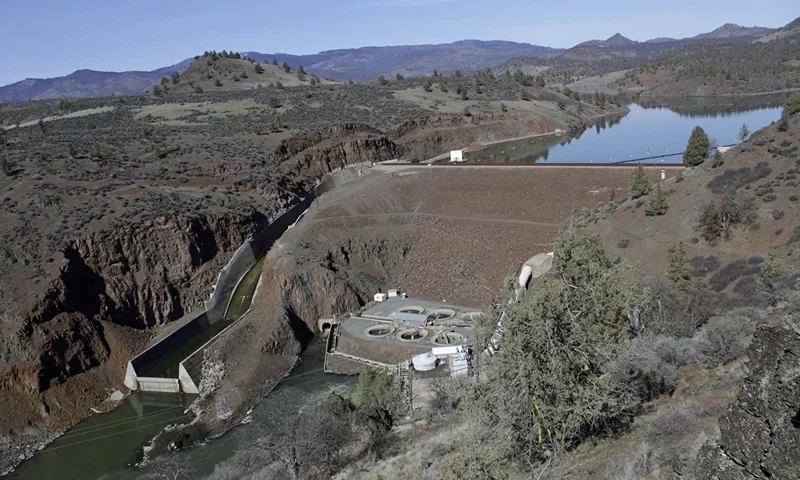 The Klamath River winds runs along state Highway 96 on June 7, 2021, near Happy Camp, Calif. Work has begun on removing four dams along the Klamath River, the largest dam removal project in history. All the dams are scheduled to come down by the end of 2024. (AP Photo/Nathan Howard, File)