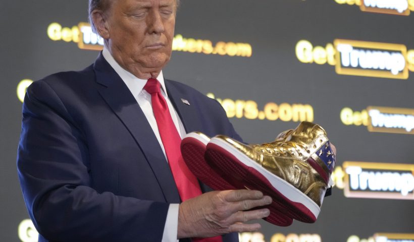 Republican presidential candidate former President Donald Trump holds gold Trump sneakers at Sneaker Con Philadelphia, an event popular among sneaker collectors, in Philadelphia, Saturday, Feb. 17, 2024. (AP Photo/Manuel Balce Ceneta)