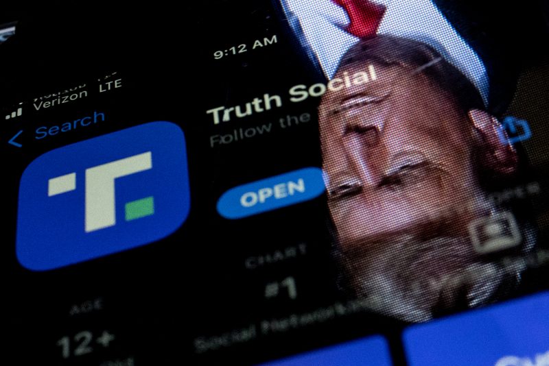This photo illustration shows an image of former President Donald Trump reflected in a phone screen that is displaying the Truth Social app, in Washington, DC, on February 21, 2022. - Donald Trump's new social media app started a gradual rollout late February 21st and should be 