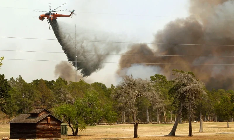 Wildfires Devastate Drought-Stricken Central Texas BASTROP, TX - SEPTEMBER 6: Firefighting helicopters dump water and flame retardant after loading up with water from a pond at Lost Pines Golf Club as they fight a fire in Bastrop State Park September 6, 2011 in Bastrop, Texas. Several large wildfires have been devastating Bastrop County for the last two days. (Photo by Erich Schlegel/Getty Images)