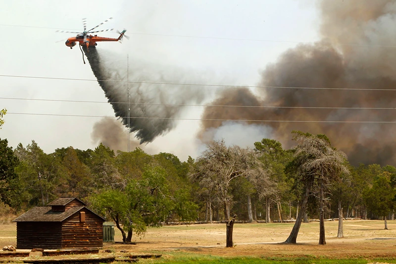 Wildfires Devastate Drought-Stricken Central Texas
BASTROP, TX - SEPTEMBER 6: Firefighting helicopters dump water and flame retardant after loading up with water from a pond at Lost Pines Golf Club as they fight a fire in Bastrop State Park September 6, 2011 in Bastrop, Texas. Several large wildfires have been devastating Bastrop County for the last two days. (Photo by Erich Schlegel/Getty Images)