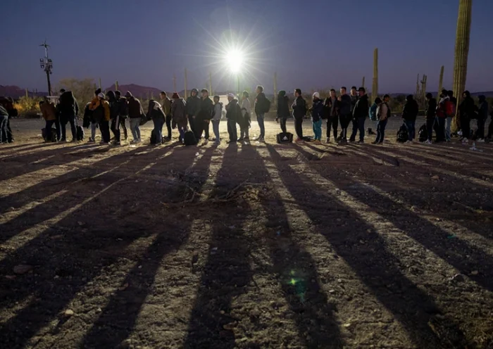 LUKEVILLE, ARIZONA - DECEMBER 07: Immigrants line up at a remote U.S. Border Patrol processing center after crossing the U.S.-Mexico border on December 07, 2023 in Lukeville, Arizona. A surge of immigrants illegally passing through openings cut by smugglers int the border wall has overwhelmed U.S. immigration authorities, causing them to shut down several international ports of entry so that officers can help process the new arrivals. (Photo by John Moore/Getty Images)