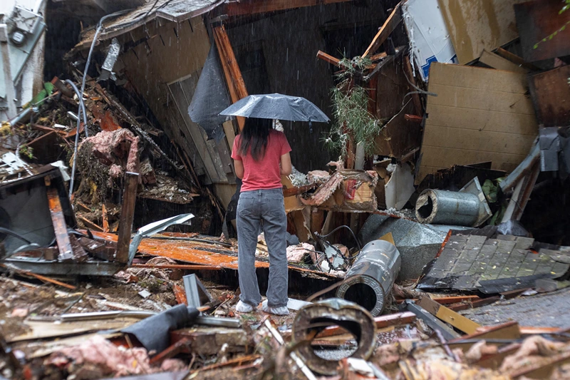 TOPSHOT-US-WEATHER-STORM-CALIFORNIA-FLOODING
TOPSHOT - A woman stands among the wreckage of a house that was abruptly destroyed by a landslide as a historic atmospheric river storm inundates the Hollywood Hills area of Los Angeles, California, on February 6, 2024. A powerful storm lashing California has left at least three people dead and caused devastating mudslides and flooding, after dumping months' worth of rain in a single day. (Photo by DAVID MCNEW / AFP) (Photo by DAVID MCNEW/AFP via Getty Images)