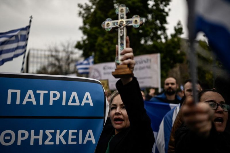 A protester brandishes a cross during a demonstration against a reform legalising same-sex marriage and adoption, that will be debated by parliament next week, in Athens on February 11, 2024. Some 4,000 people according to police responded to a call by Orthodox religious groups. They gathered on central Syntagma Square, waving Greek flags and brandishing crosses and banners opposing same-sex parenthood. (Photo by Aris MESSINIS / AFP) (Photo by ARIS MESSINIS/AFP via Getty Images)